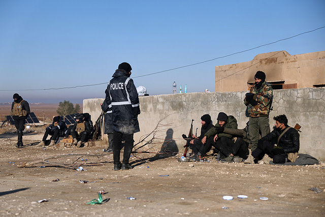 Сирийские правительственные войска со своим багажом ожидают входа в лагерь аль-Холь в провинции аль-Хасаке на северо-востоке Сирии